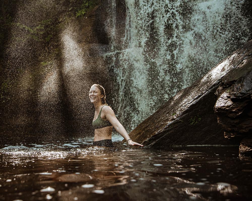 a woman standing under a waterfall in water